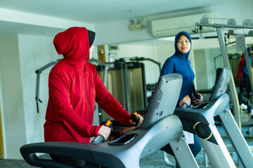 Muslim sport, Happy cheerful Asian Muslim mother and daughter Running on Treadmill. Energetic Fit...