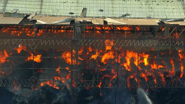 Amidst roaring flames, firefighters battle a fierce inferno devouring an industrial complex. Torrents of water assail the blaze, billowing smoke veiling their valiant efforts.
