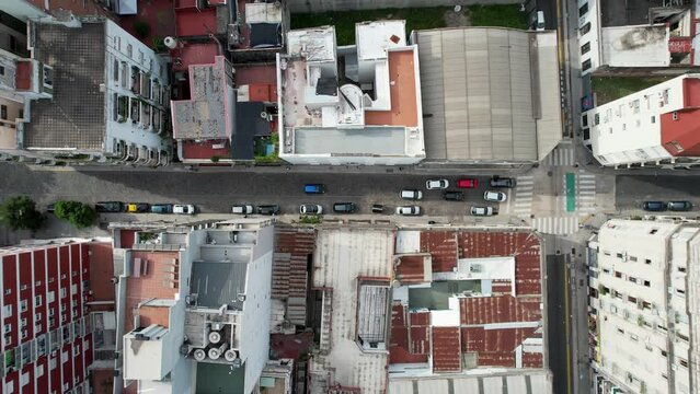 Auto azul llega a sem&aacute;foro y se pone detr&aacute;s de la fila de autos. Vista de dron cenital de cruce de calles en ciudad, barrio. Trafico, vista a&eacute;rea descendente.