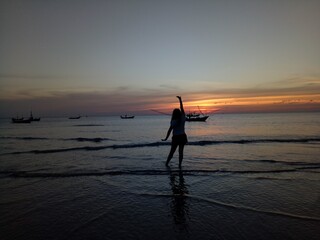 Fototapeta premium person walking on the beach at sunset