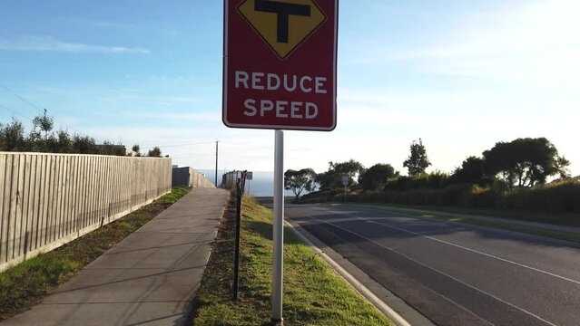 The text on a red sign says 'reduce speed' with a T-intersection warning on the roadside. VIC Australia