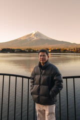 Fototapeta premium man tourist with Fuji Mountain at Lake Kawaguchi, happy Traveler sightseeing Mount Fuji in Fujikawaguchiko, Yamanashi, Japan. Landmark for tourists attraction. Japan Travel, Destination and Vacation