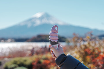 Woman hand holding ice cream in a cone with Mt Fuji at Lake Kawaguchi, happy Traveler sightseeing...