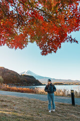 Woman tourist with Fuji Mountain at Lake Kawaguchi in Autumn season, happy Traveler travel Mount Fuji, Yamanashi, Japan. Landmark for tourists attraction. Japan Travel, Destination and Vacation