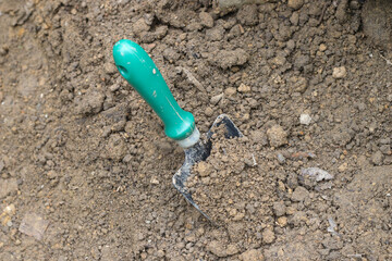 Green soil digger in the garden. Gardening activity with soil background.