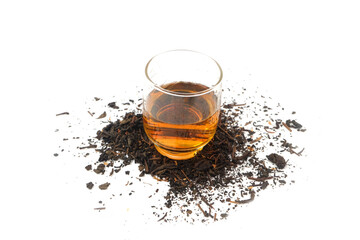 a glass of tea on dry black tea leaves