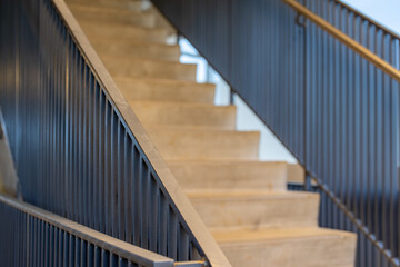Fototapeta premium Close-up photo of a modern gray metal railing and concrete stair case between floors. 