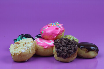 Donuts with colorful topping. Isolated purple background and copy space.