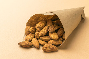 Almonds in a paper bag on a beige background.