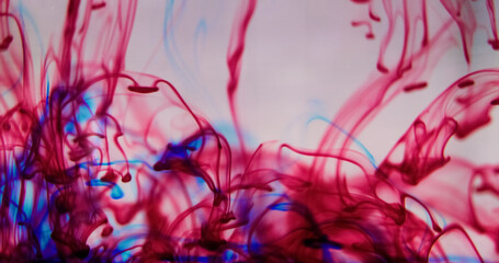 Water dye. Ink drops. Defocused red blue color splash trail paint fluid swirl liquid pigment...