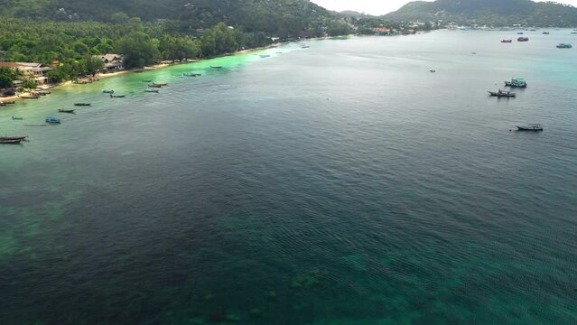 Aerial view tilting over boats, flying along the coastine of Ko Tao, Thailand