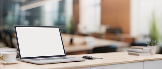 A laptop computer on a minimal wood table with a blurred background of a modern meeting room.
