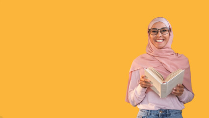Teacher portrait. Reading class. Study course. Smart cheerful woman in hijab glasses with open book isolated on orange empty space background.