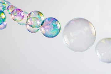 A series of ascending soap bubbles, each bubble reflecting a rainbow of colors, set against a clean, white background.