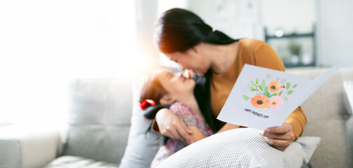 Image of  young mom receiving greeting card from her little daughter on Mother's day.