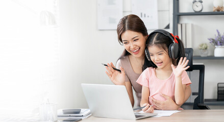 Asian little young girl with headphone learning online class at home with mother. Preschool child...
