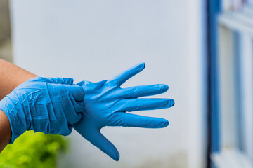 domestic nurse putting on blue gloves to heal a patient with a broken foot due to a fractured...