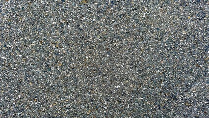 Closeup view  of a compact gravel road surface, showcasing a detailed texture of interlocked stones in a durable, gritty layout.