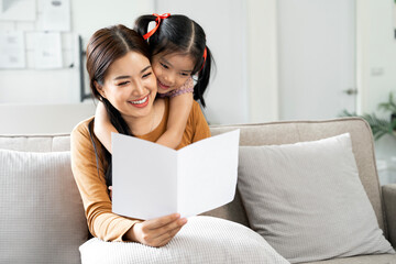 Image of  young mom receiving greeting card from her little daughter on Mother's day.