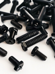 A pile of black screws on a white surface.