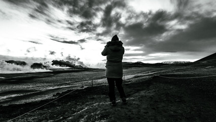 A woman looks at the landscape of Iceland with the geysers