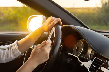 Naklejka premium Womandriver using mobile phone paying for parking and navigating in the city while stopped on the side of the road. Self road trip, technology, travel and people concept