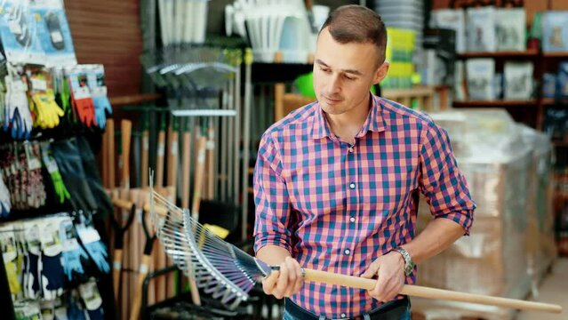 Male gardener choosing rake in a hardware store. High quality 4k footage