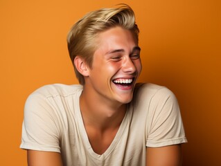 A young man with blonde hair is smiling and laughing