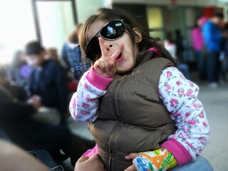 girl with sunglasses waving with peace sign in a waiting room