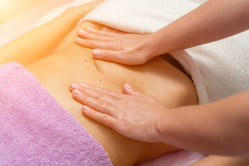 Top view of hands massaging female abdomen.Therapist applying pressure on belly. Woman receiving massage at spa salon
