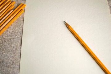 A yellow pencil rests on paper, a classic writing implement