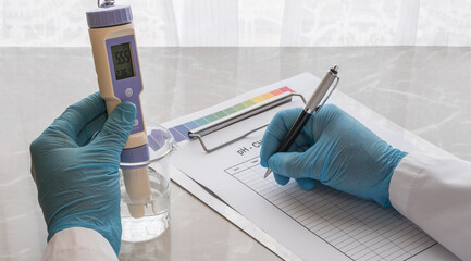 A hand of a man using glove checking the ph of water. Cheking ph . water ph