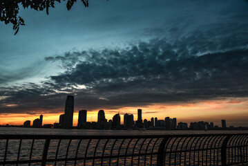Jersey City Skyline under Beautiful Sunset Skies, seen from the Battery Park - Manhattan, New York...