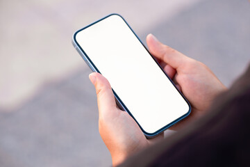 Woman's hand holds a large smartphone with a blank white screen in his hand. It shows free space...