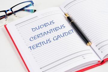 DUOBUS CERTANTIBUS TERTIUS GAUDET it means in Latin While two argue, the third rejoices. the inscription in the notebook