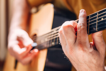 Closeup of male hands playing acoustic guitar at home