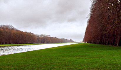 Winter Morn by Versailles: The Grand Canal Bathed in Reddish Hues Under Cloudy Skies, a Serene...