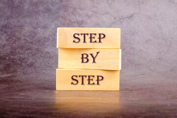 Concept Step by Step text written on wooden blocks on a dark background
