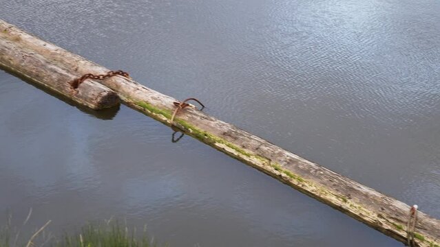 Tranquil Water Scene with Aged Wooden Log and Rusty Chains