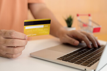 Man holding a credit card and using laptop for online shopping