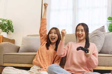 Lifestyle at home concept, LGBT lesbian couple making win gesture while playing game with joystick