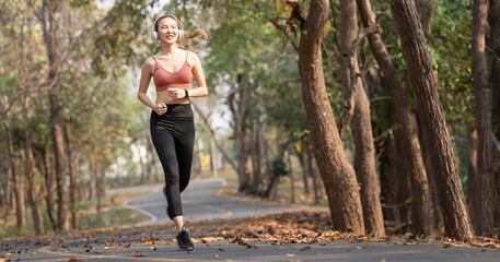 Young beautiful asian female in sports bra with headphone running outdoor. Workout exercise in the morning.