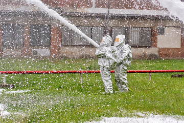 Firefighters in special heat protective suits use foam to extinguish a tank of highly flammable liquid methanol
