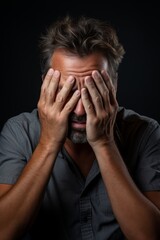 Stressed man covering face with hands
