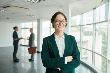 Portrait of smiling confident female entrepreneur standing in new spacious office