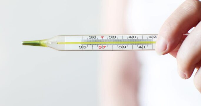 mercury thermometer in a woman's hand on a light background
