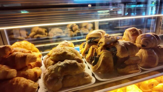 4k video footage of Various types of bread on display in a bakery or pastry such as macarons, croissants and danish. Modern bakery with different kinds of Loaf, bread, cakes and buns.