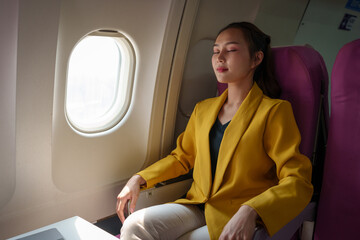 Attractive Asian businesswoman passenger is on a business class luxury plane while sit and rest...
