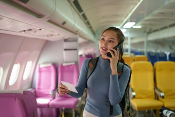 Confident Asian female traveler traveling by plane A passenger wearing a backpack uses a smartphone...