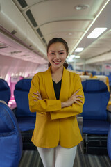 Beautiful successful Asian businesswoman standing with arms crossed. Smiling confidently in the airplane aisle When traveling abroad for a first class business presentation business tourism concept.